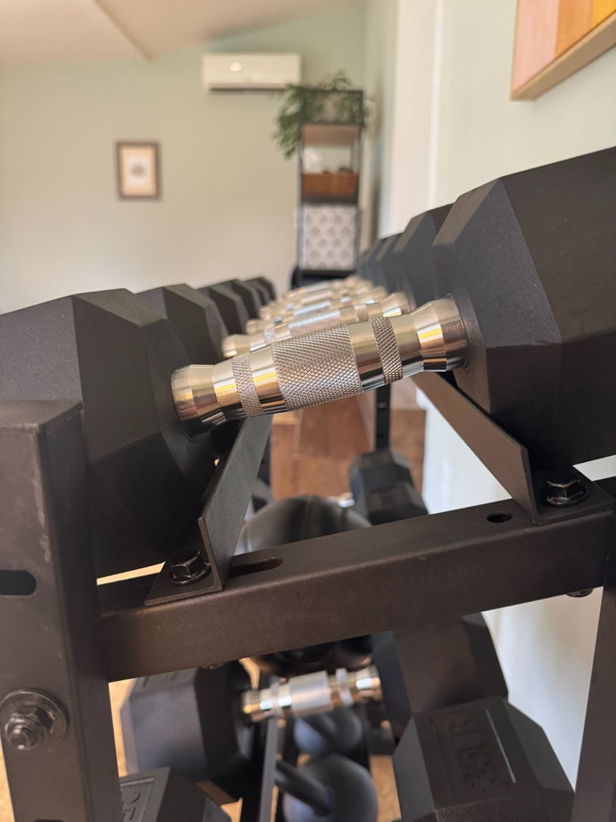 Knurled steel dumbbell handles lined up on the studio rack