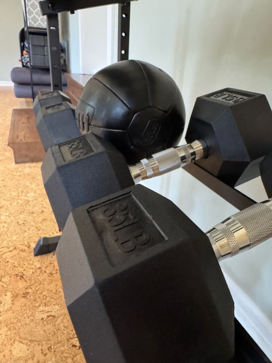 Close-up of hex dumbbells and a medicine ball on the studio rack