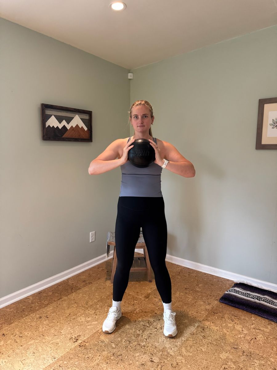 Sadie standing with a medicine ball held at chest height