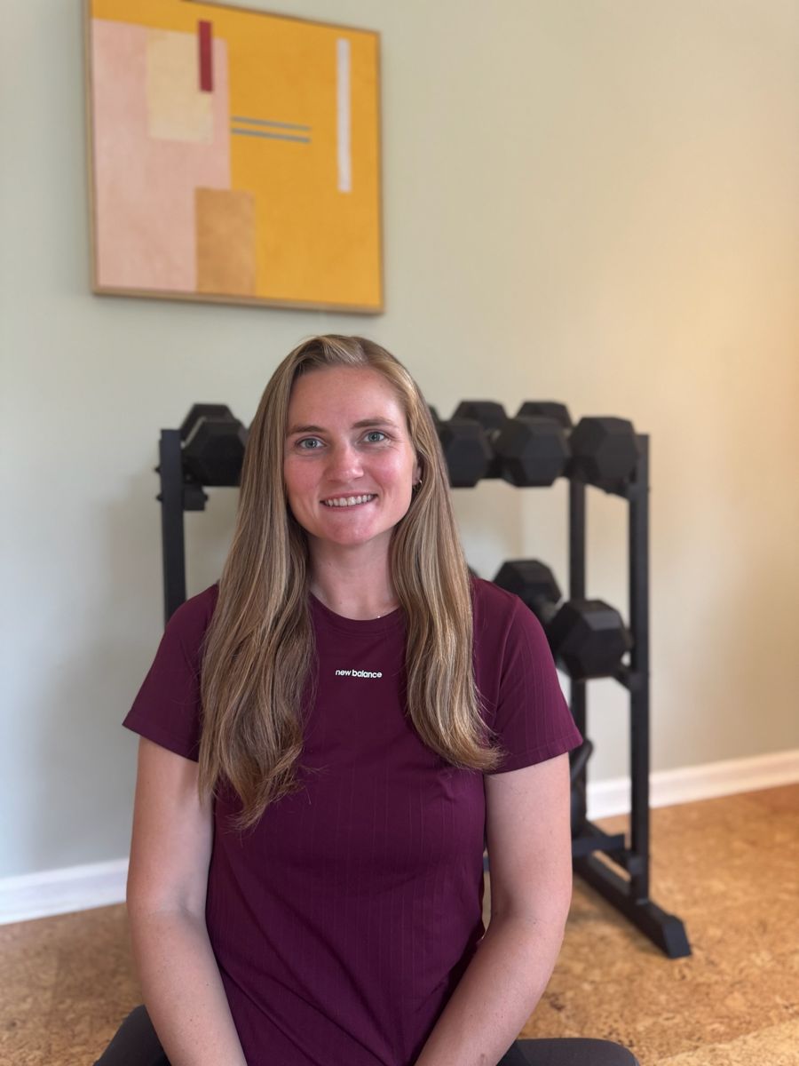 Sadie smiling in front of the dumbbell rack
